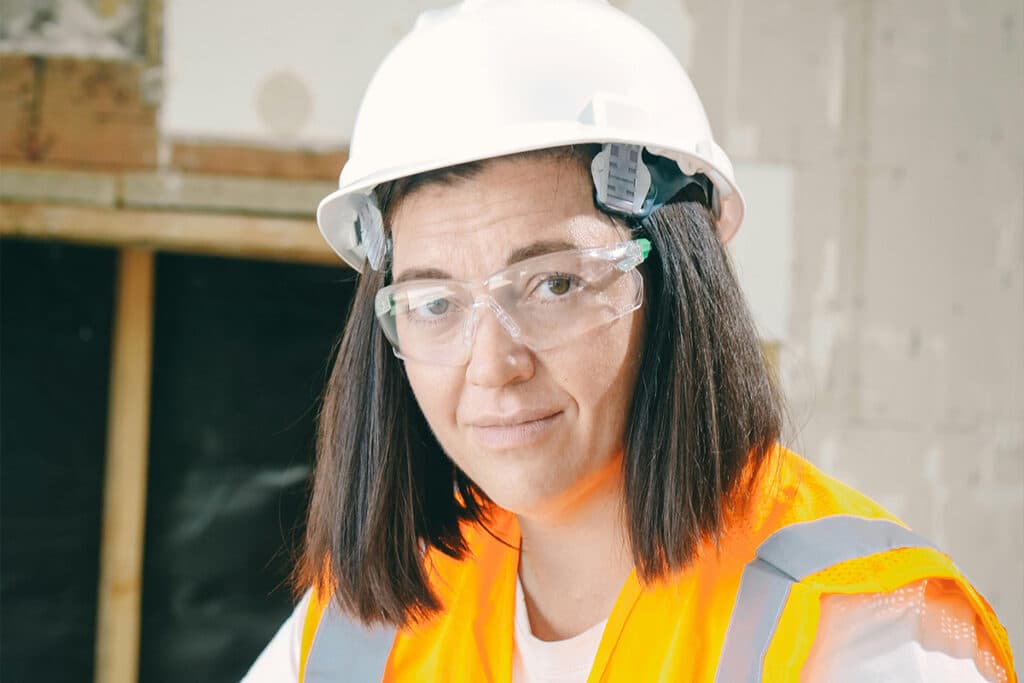 A woman holding a pipe wrench, showcasing plumbing skills, essential for how to become a plumber.