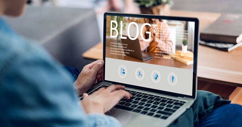 Man typing on a laptop working on blog