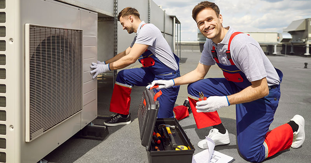 smiling hvac technicians use equipment on roof