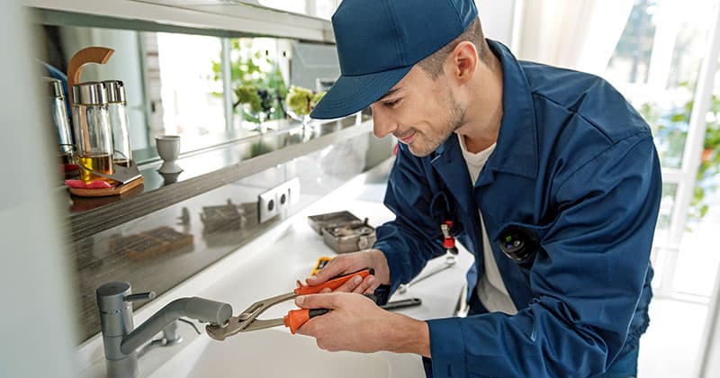 Handyman works on a sink with wrench